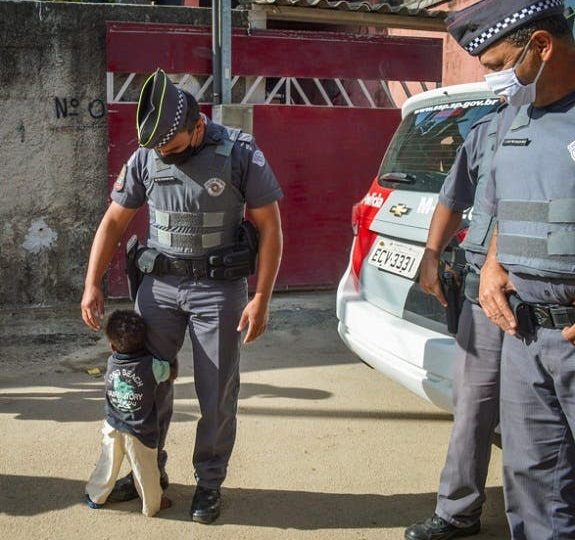 Menininho abraça policial depois de receber cesta básica em Itaquaquecetuba-SP