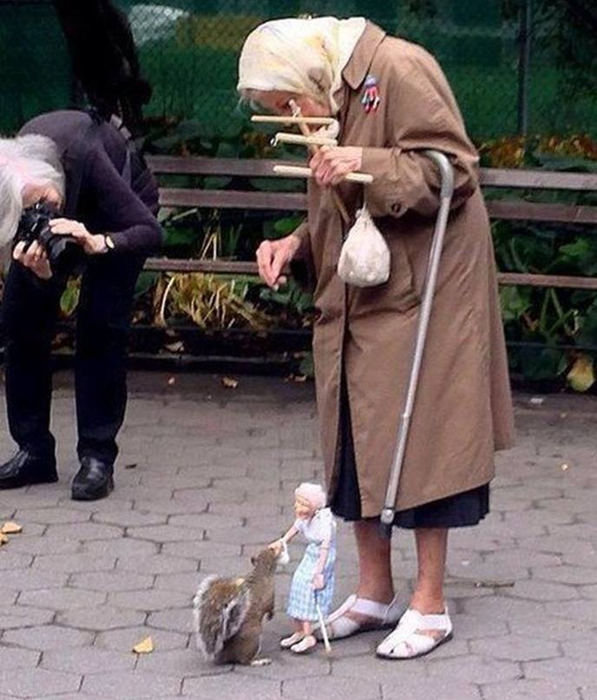 Velha senhora alimenta esquilos com marionete de si mesma